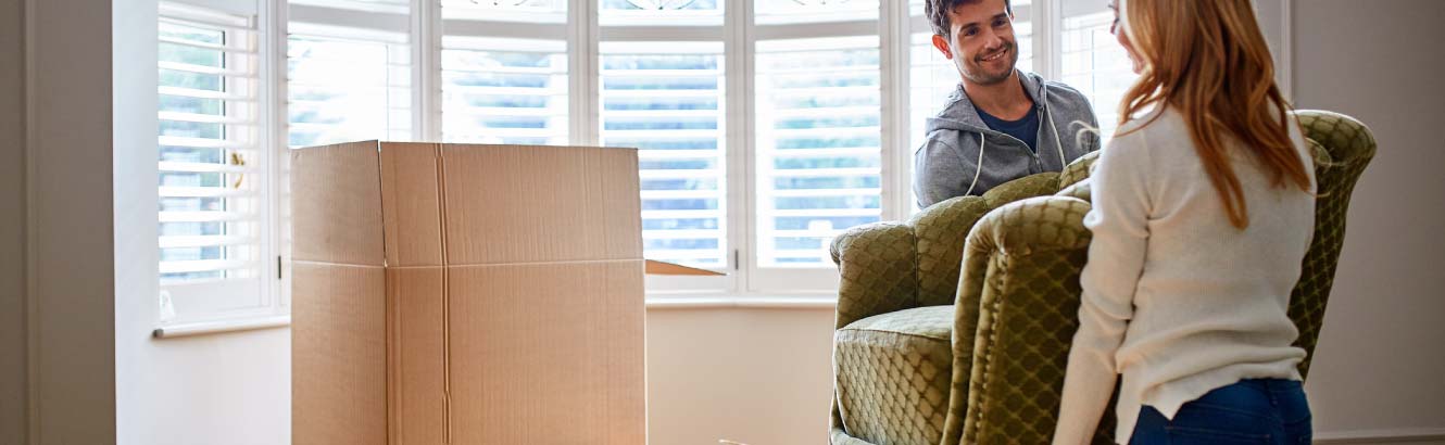 a couple moving a chair into their new house